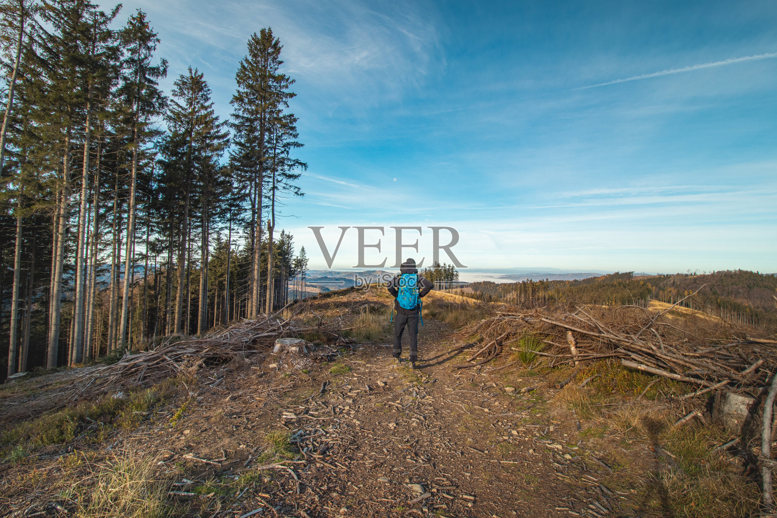 在捷克共和国的拜斯基迪山脉，一个背着蓝色背包的旅行者走向他难忘的经历。清晨的阳光照亮了一片空地照片摄影图片