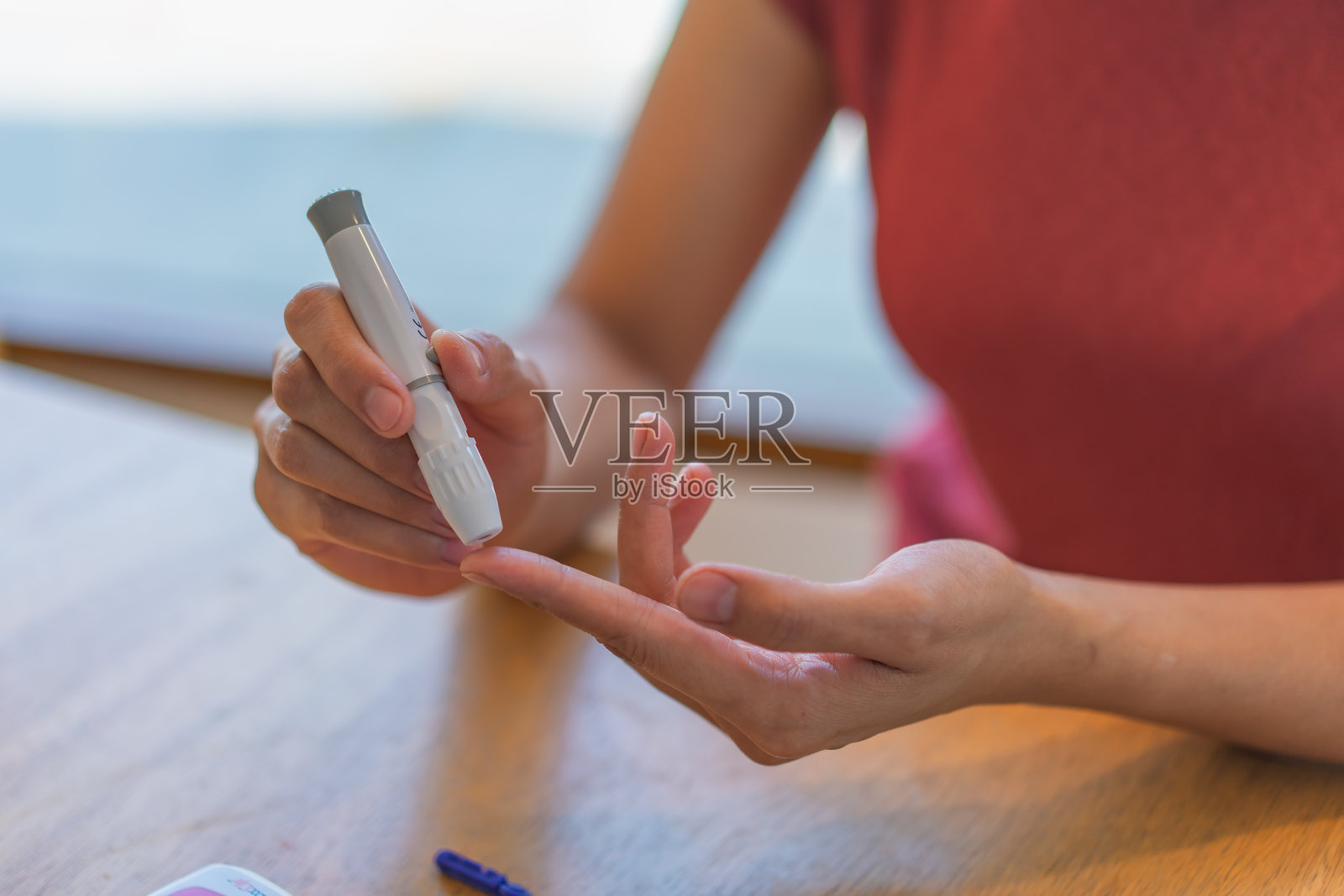 年轻女子在家里做健康检查时使用血液检测试剂盒。家庭手指刺血测试。近距离、糖尿病概念、老年保健、照片摄影图片