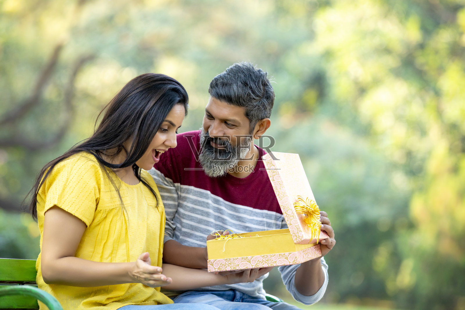 年轻男子在公园给年轻女子惊喜礼物。照片摄影图片