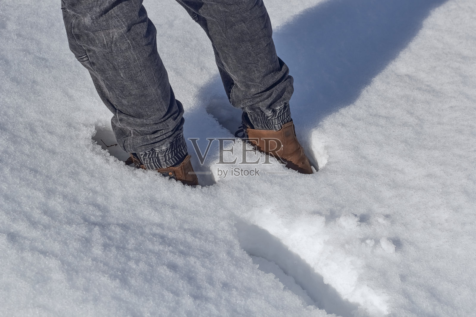 穿着靴子的脚在雪地里。照片摄影图片