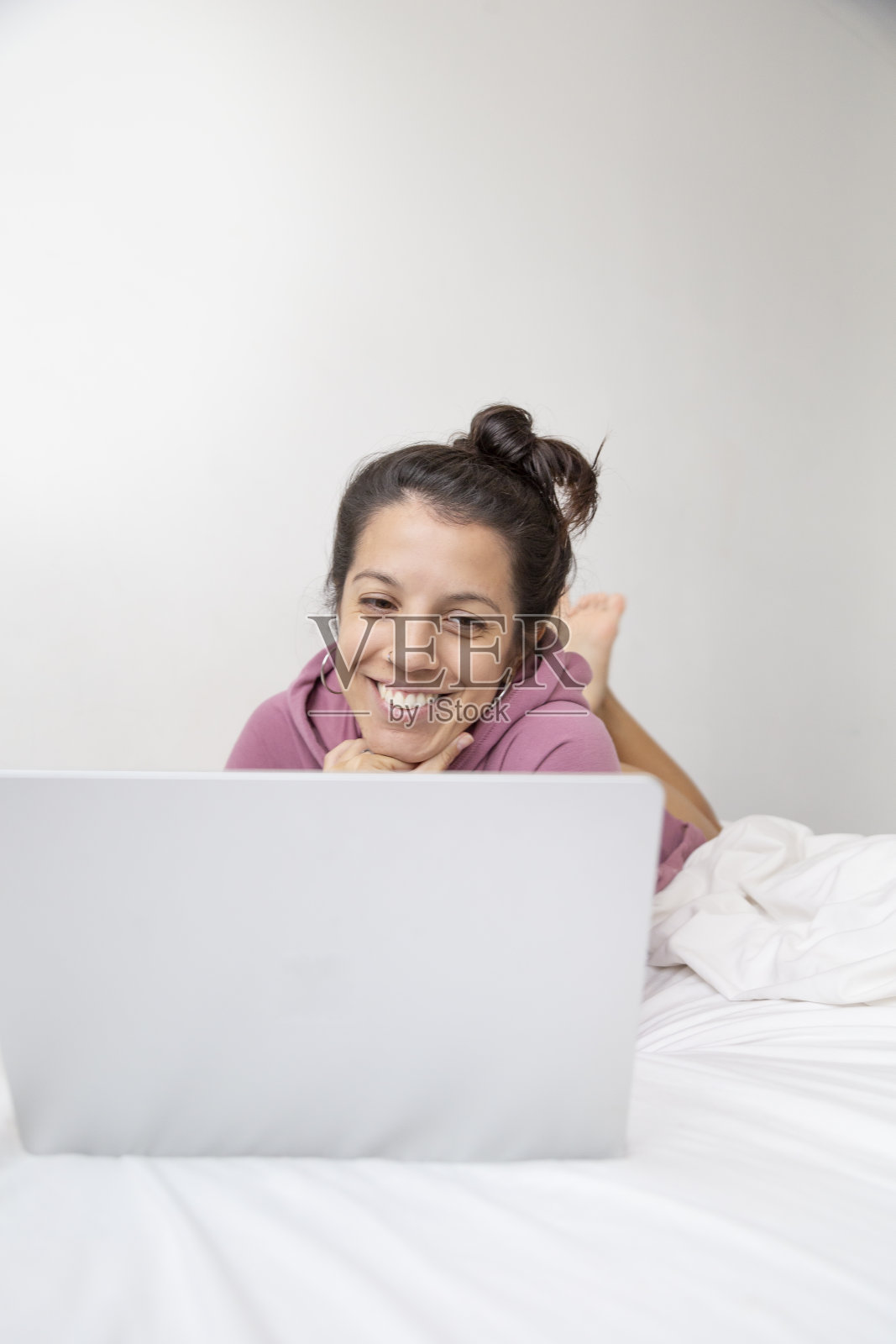 白人妇女在白色床单的床上使用笔记本电脑照片摄影图片