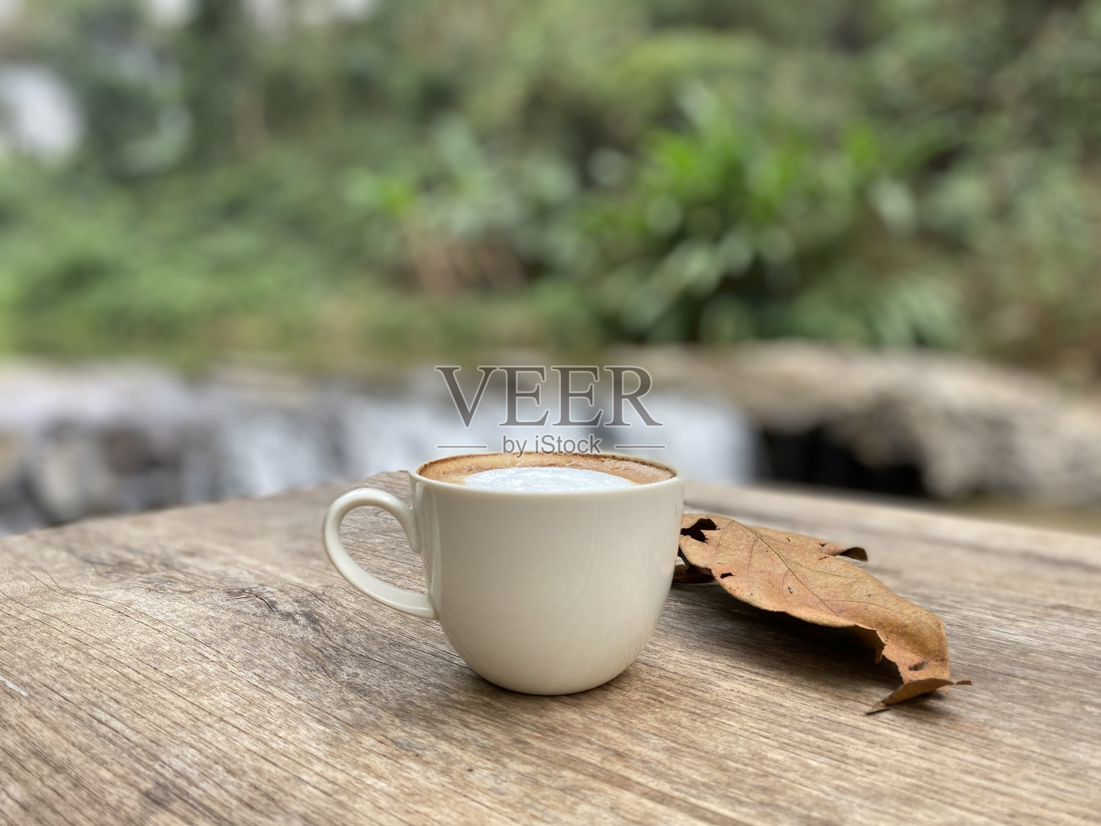 一杯咖啡放在木桌上，背景是自然照片摄影图片