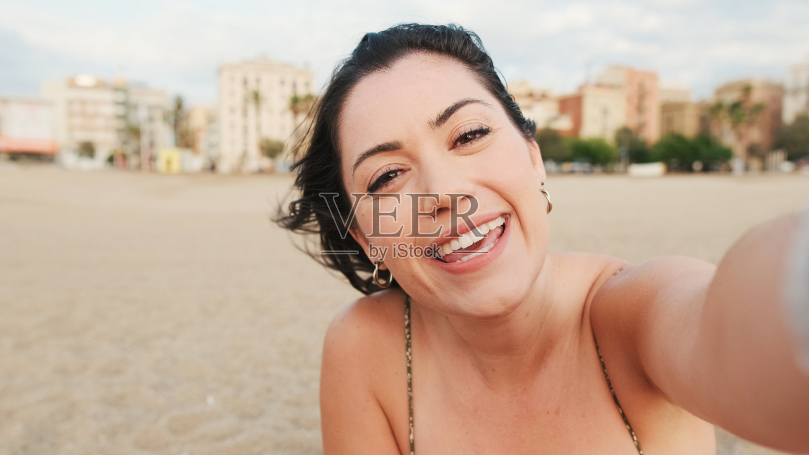 年轻女子坐在沙滩上，用手机，视频通话照片摄影图片