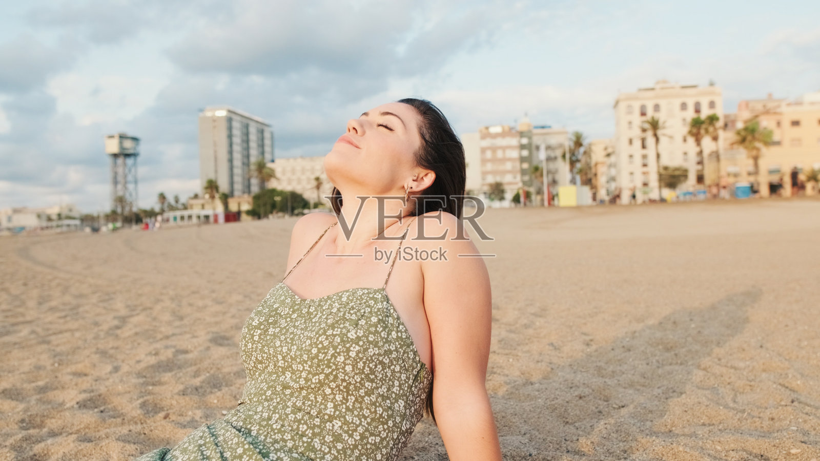 年轻女子坐在沙滩上享受着好天气照片摄影图片