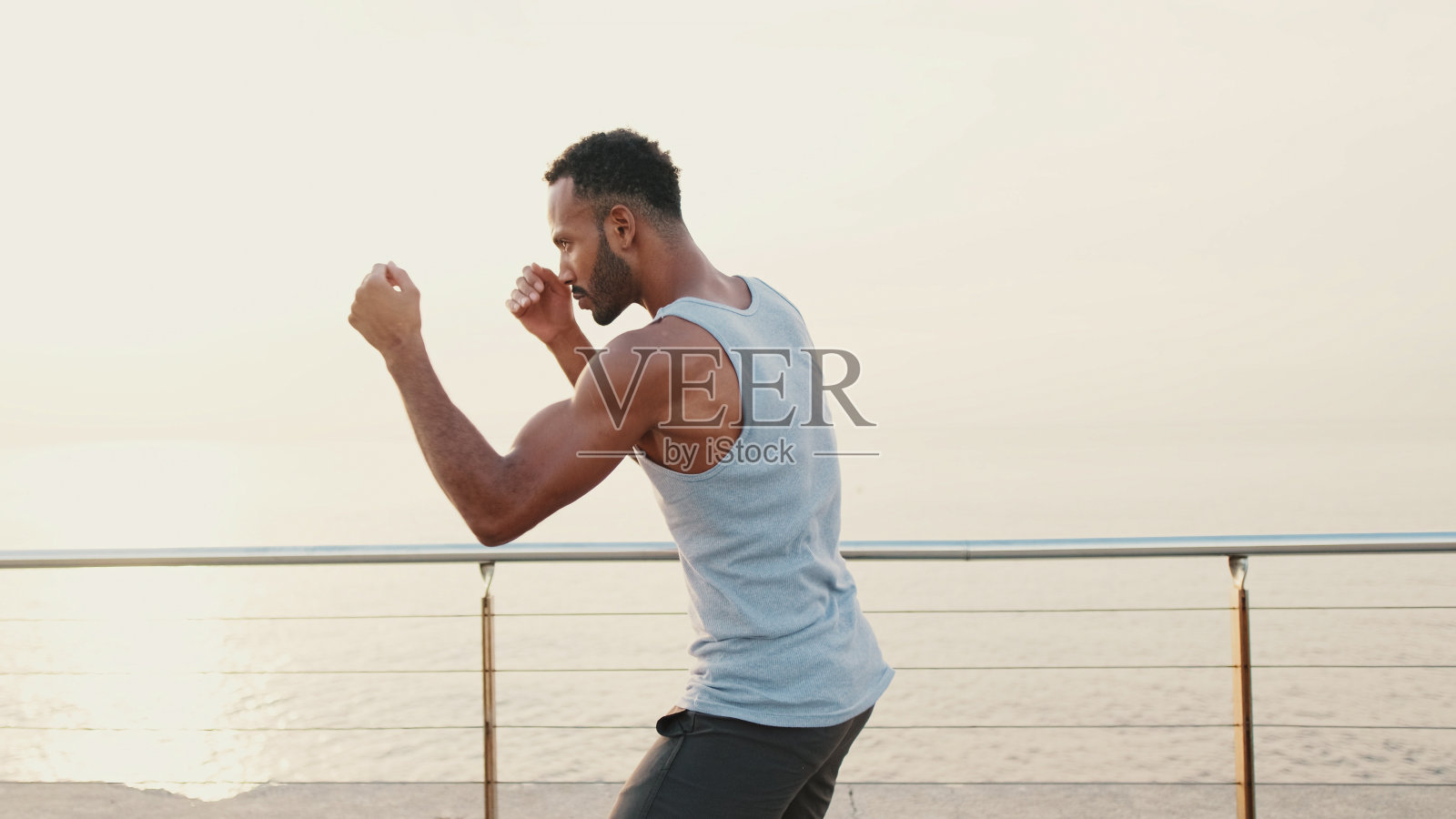 年轻的胡须男性适合运动员拳击手练习拳击技术，站在堤岸上照片摄影图片