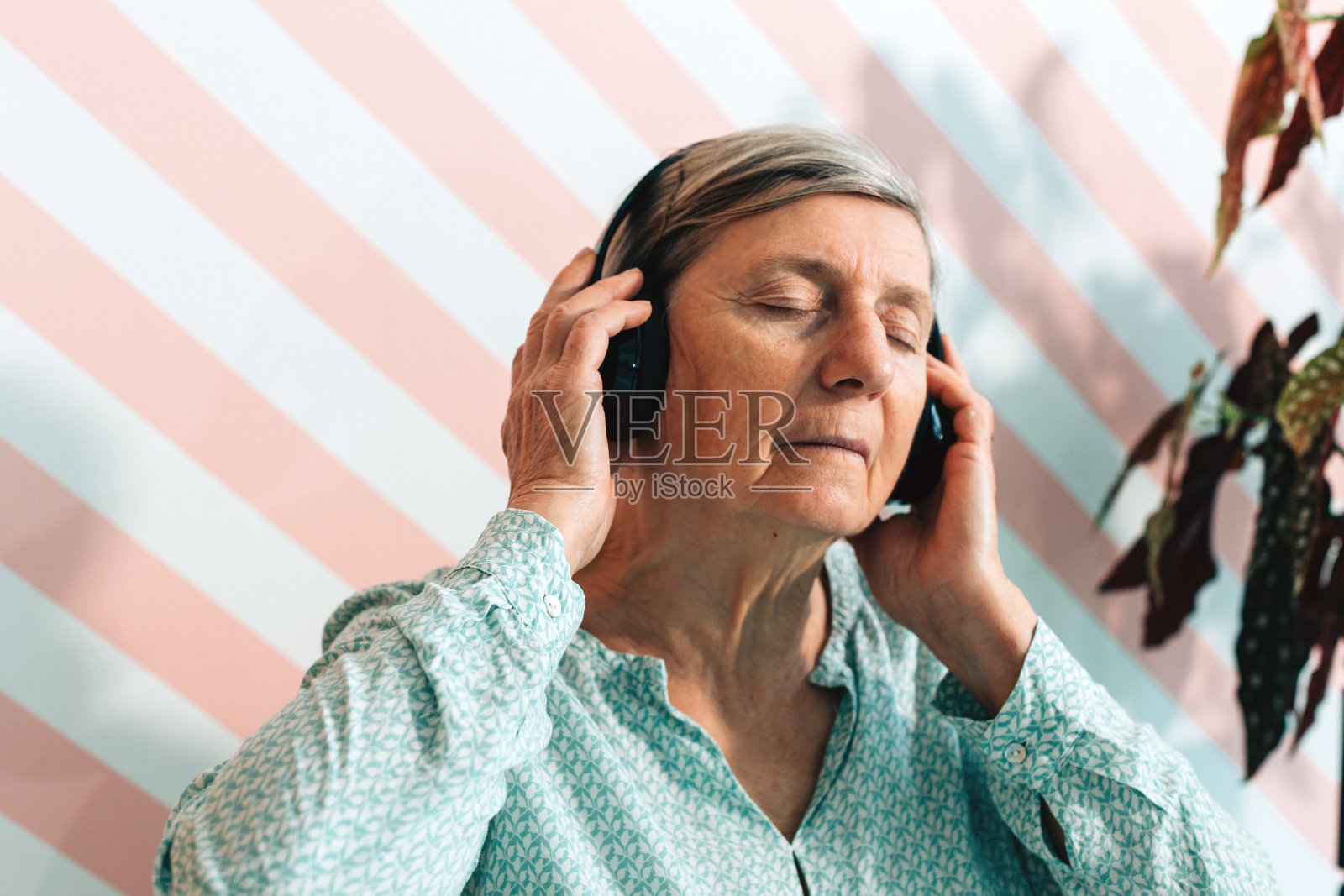 一位老妇人闭着眼睛热情地听着音乐照片摄影图片