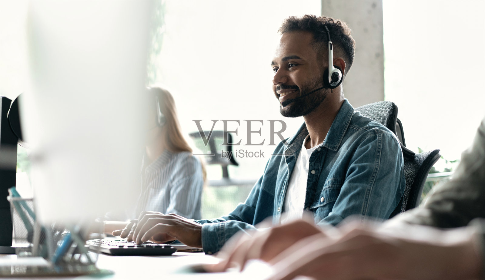 快乐的年轻男性客户支持主管在办公室工作照片摄影图片