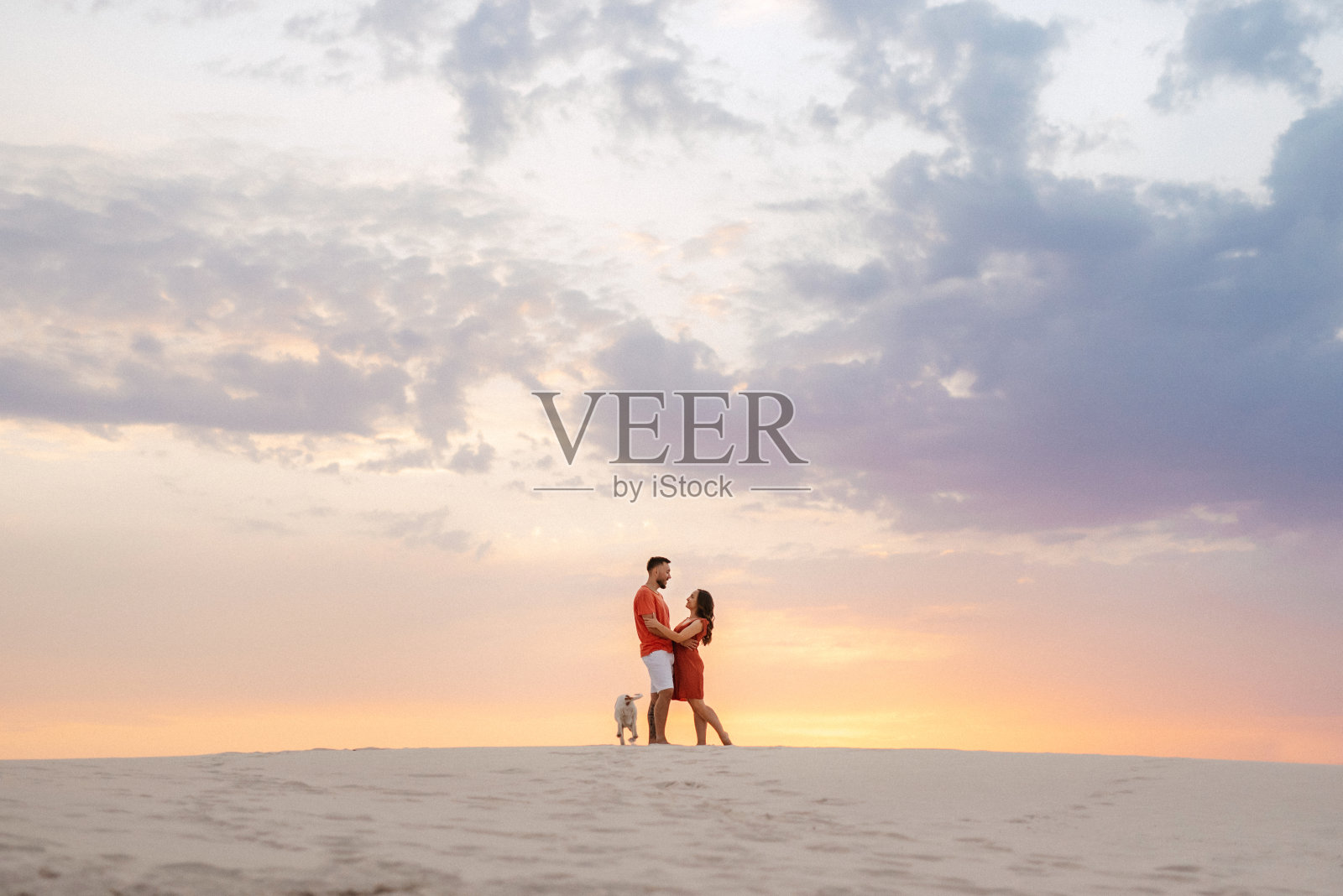 穿着橙色衣服的年轻夫妇带着狗照片摄影图片