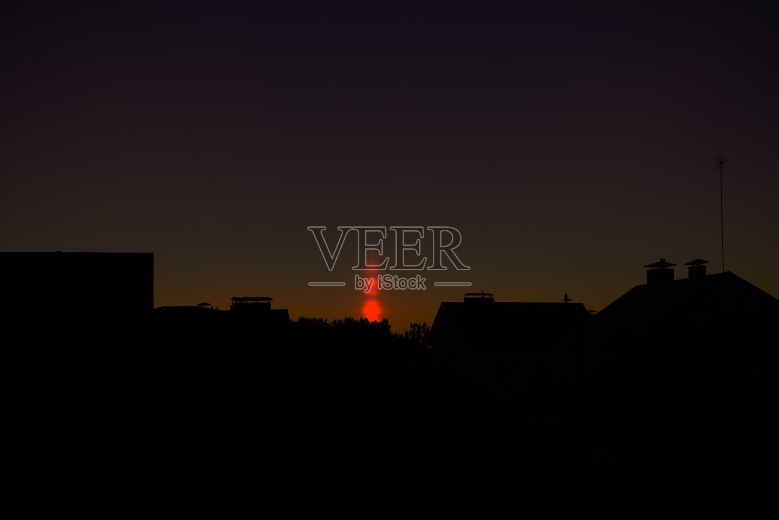 光柱的自然现象。视觉大气现象，光学效果，太阳在日落时在空气中折射。屋顶上美丽的日落天空。横幅、海报照片摄影图片