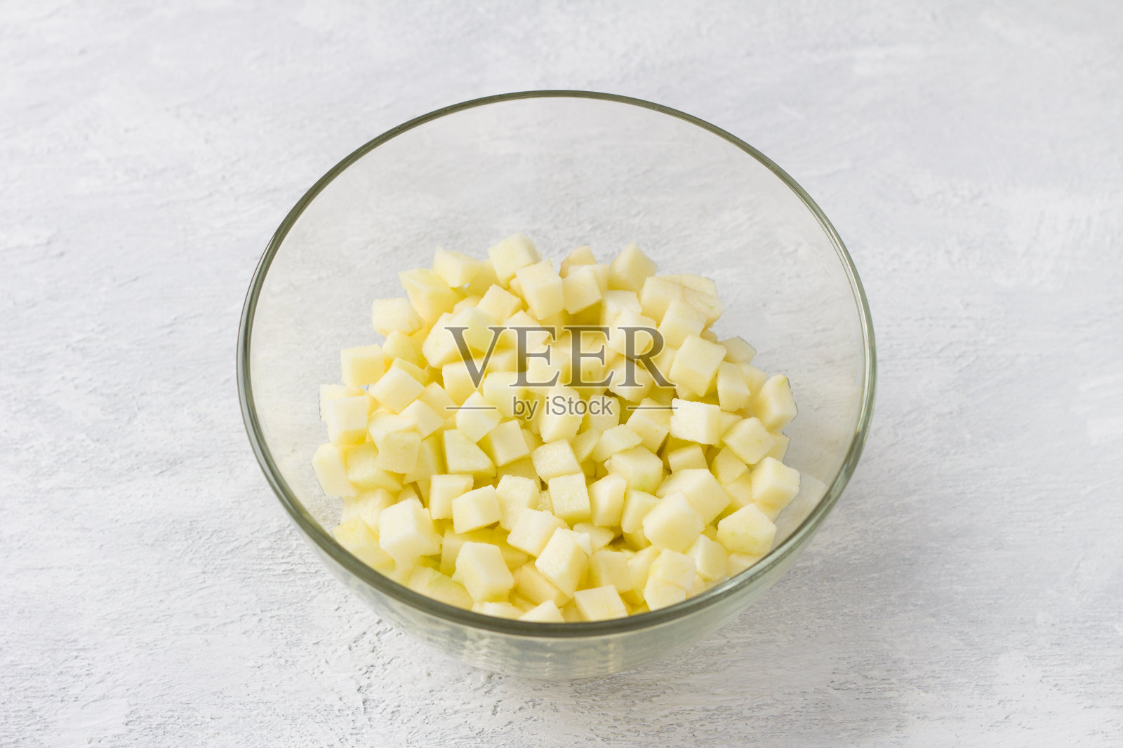 浅灰色背景上有苹果丁的玻璃碗。自制美食照片摄影图片