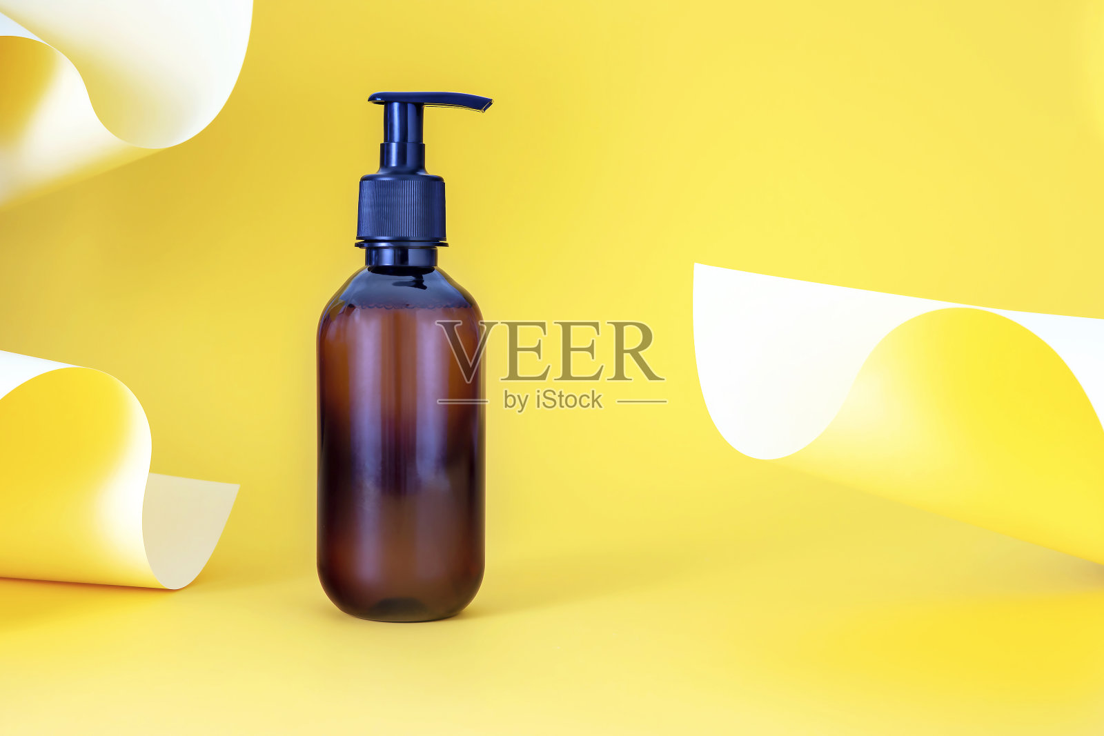 在一个抽象的背景与彩纸化妆品泵瓶的模型照片摄影图片