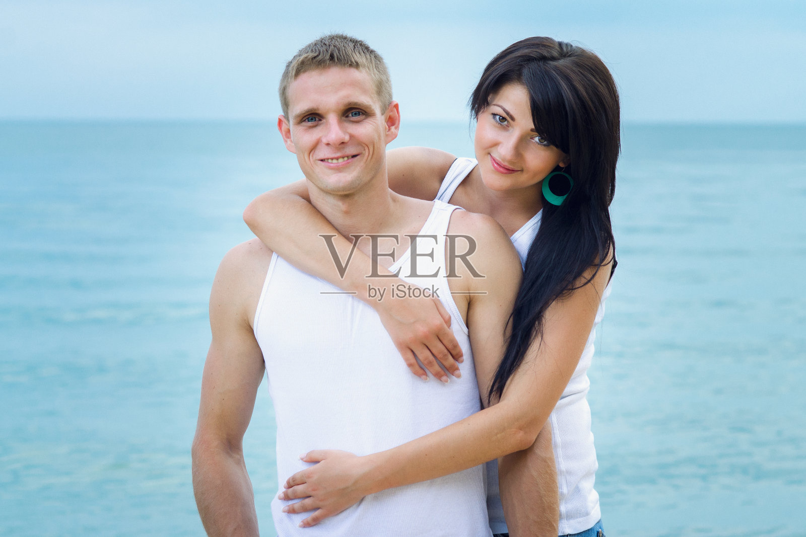 一个男孩和一个穿牛仔裤和白t恤的女孩在海滩上照片摄影图片