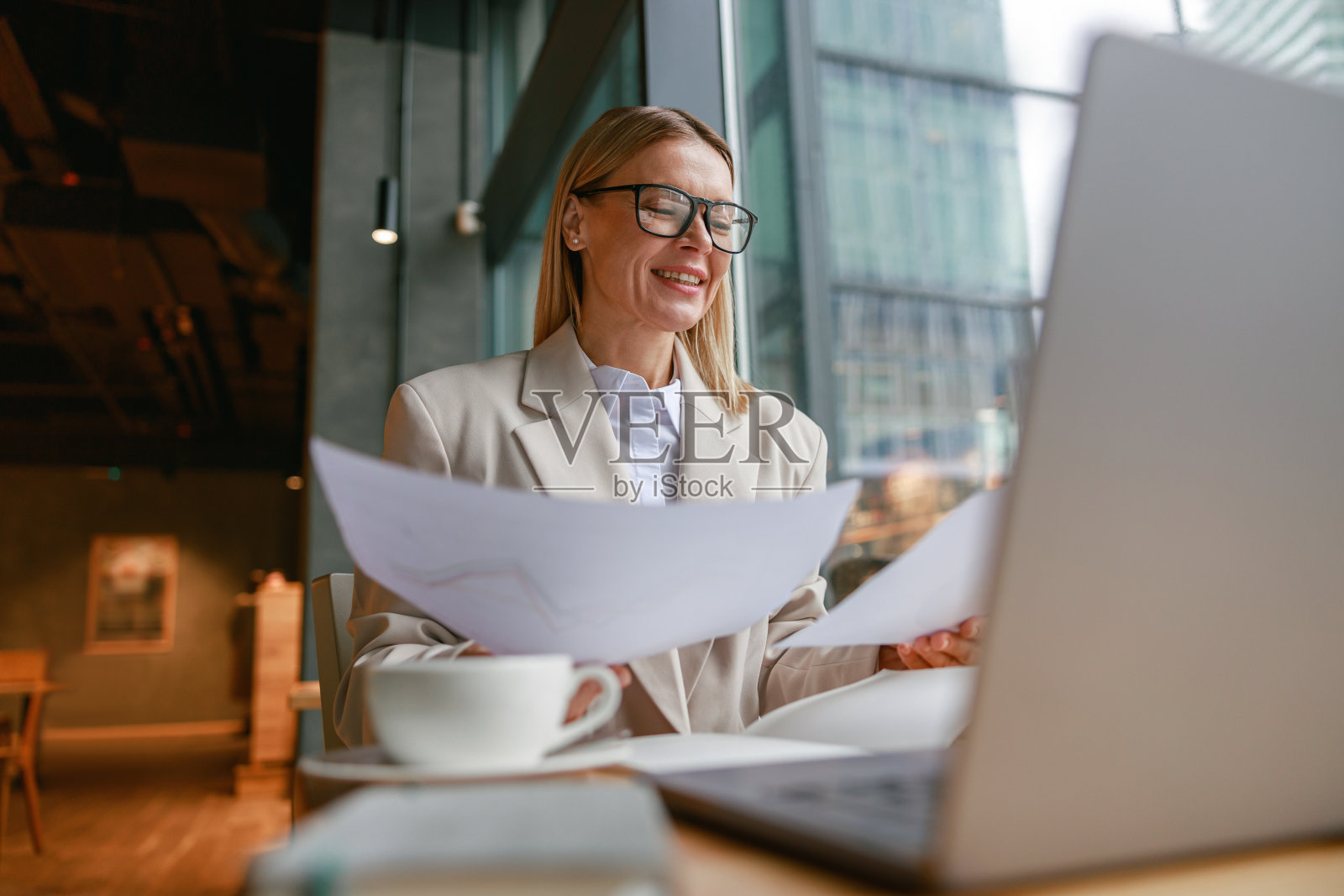 聪明的女商人戴着眼镜，坐在咖啡馆里处理文件和使用笔记本电脑照片摄影图片