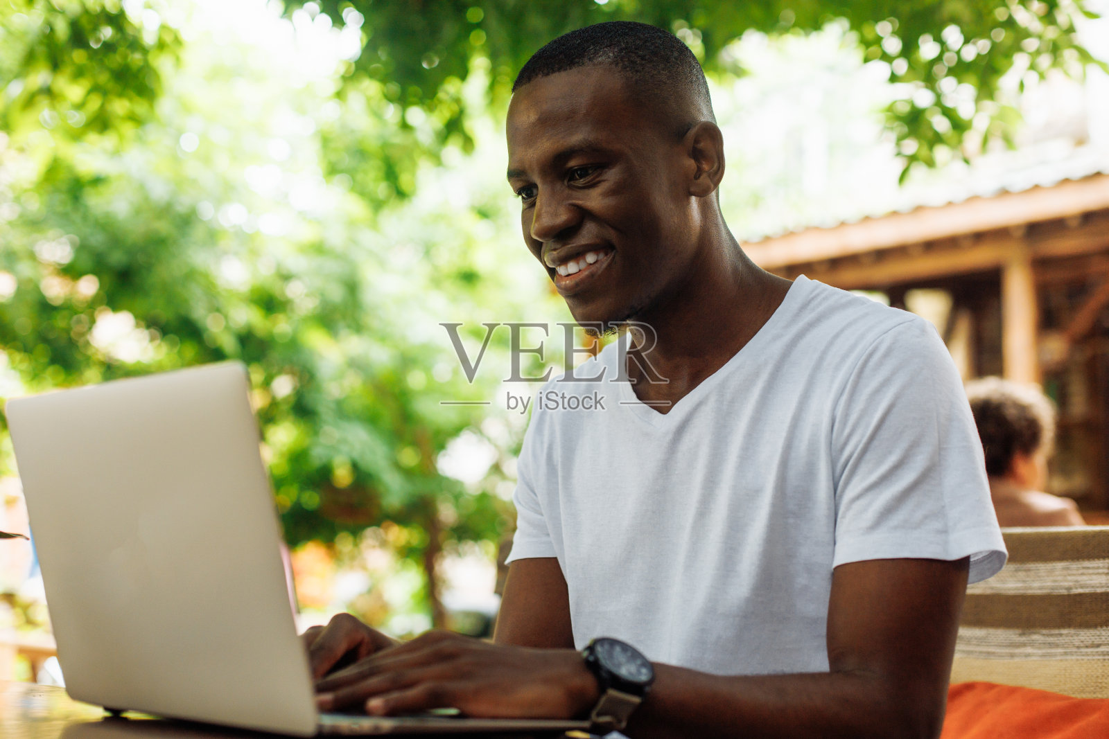 特写笑的混合种族商人，使用笔记本电脑，在街头咖啡馆作为自由技术工作者在线工作。照片摄影图片