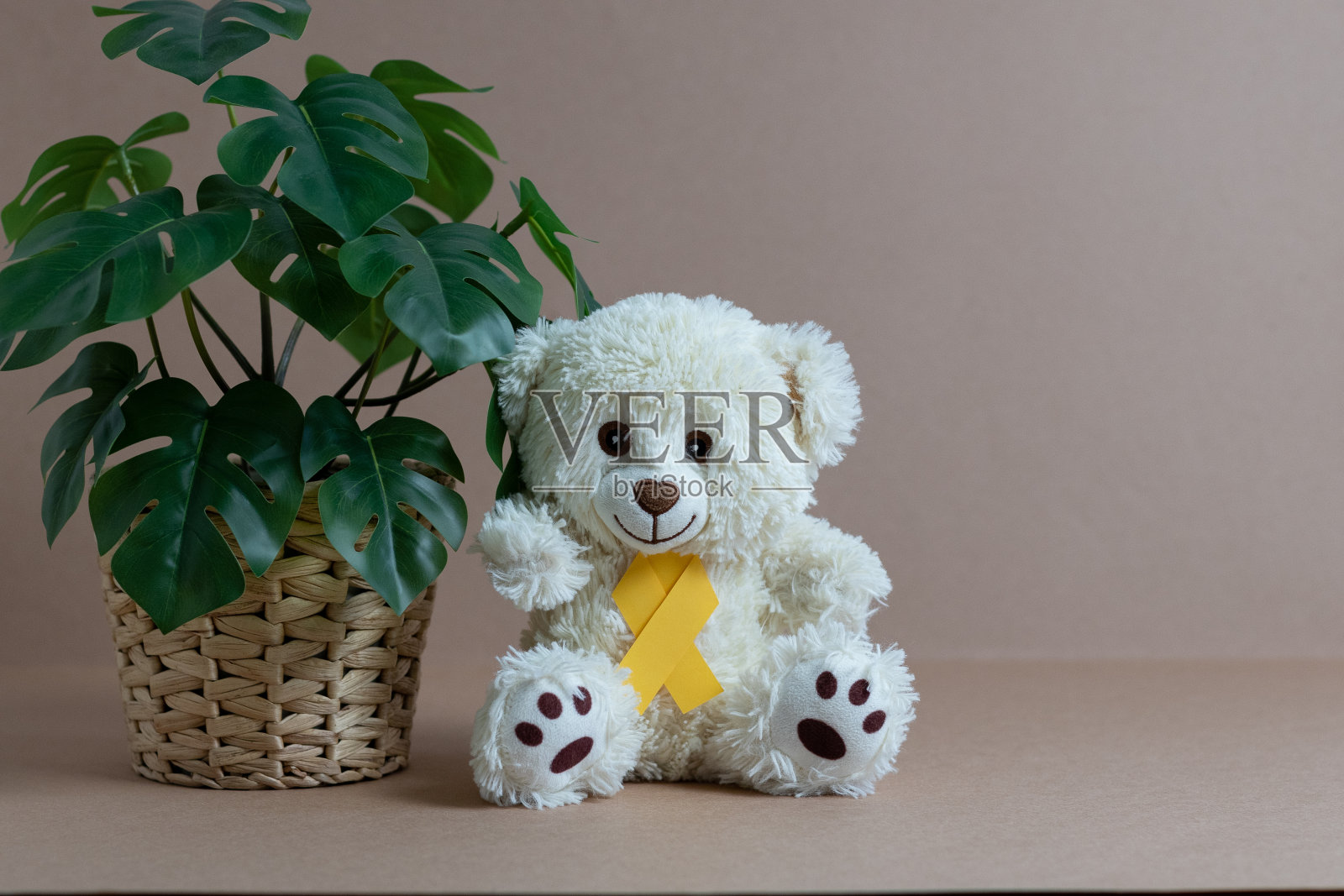 玩具熊与黄色丝带在裸色的背景。照片摄影图片