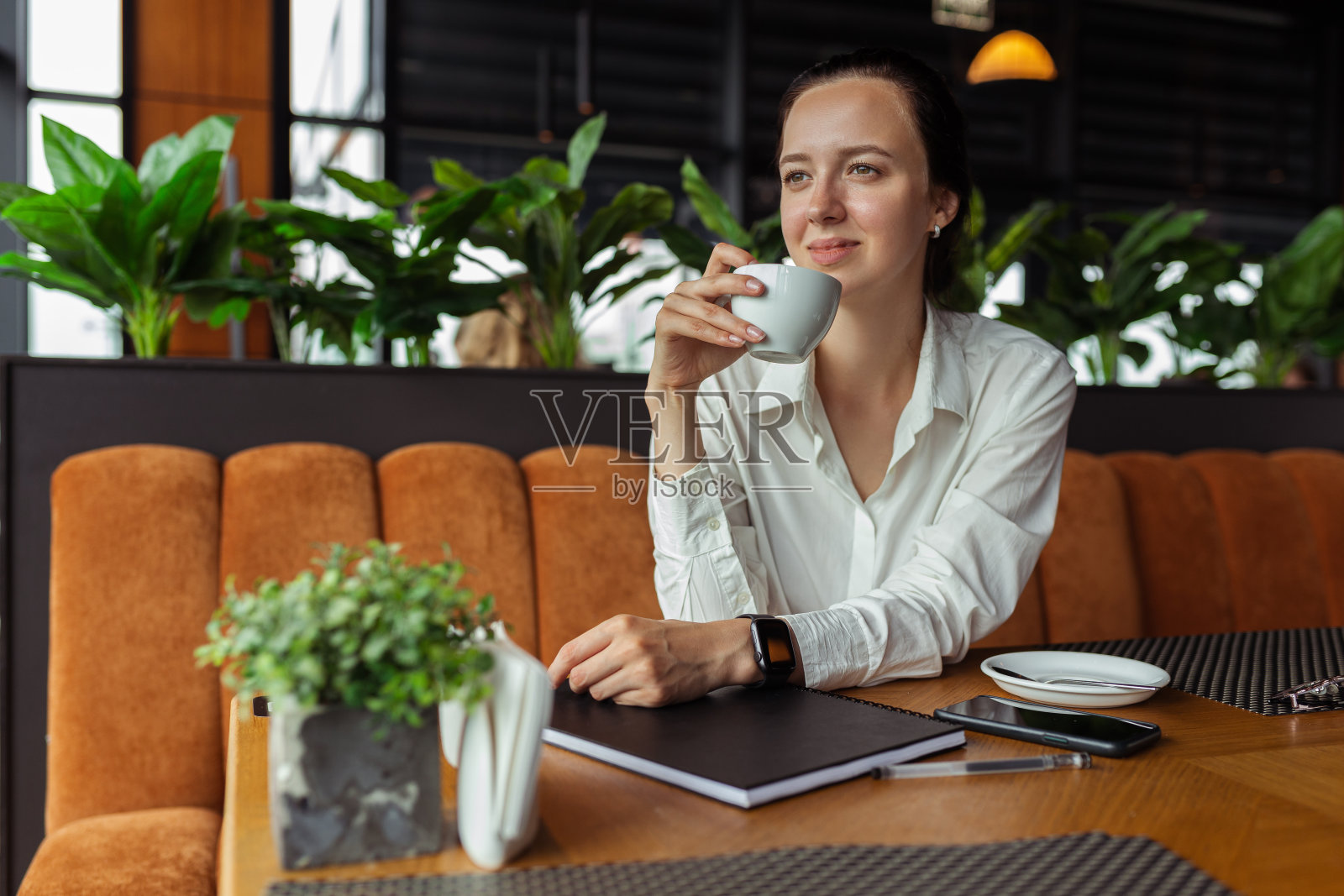 微笑的女餐厅经理在桌子上喝咖啡照片摄影图片