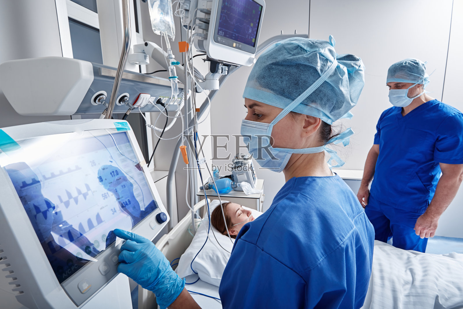 医院护士在重症监护室检查女病人，并使用医疗设备和传感器监测她的健康状况。加护病房照片摄影图片