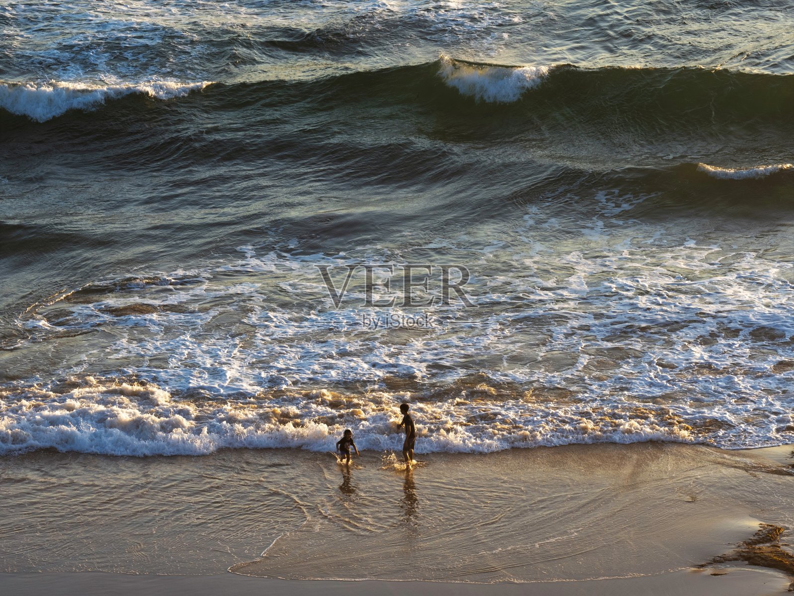 远处孩子的剪影在海滩上玩耍照片摄影图片