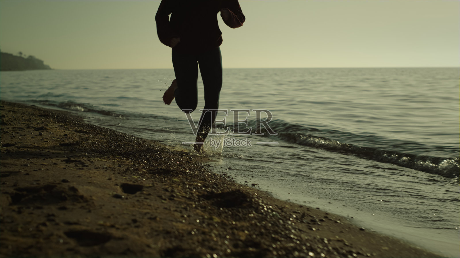 不知名的女孩慢跑沙滩。苗条的女人在夕阳下奔跑。照片摄影图片