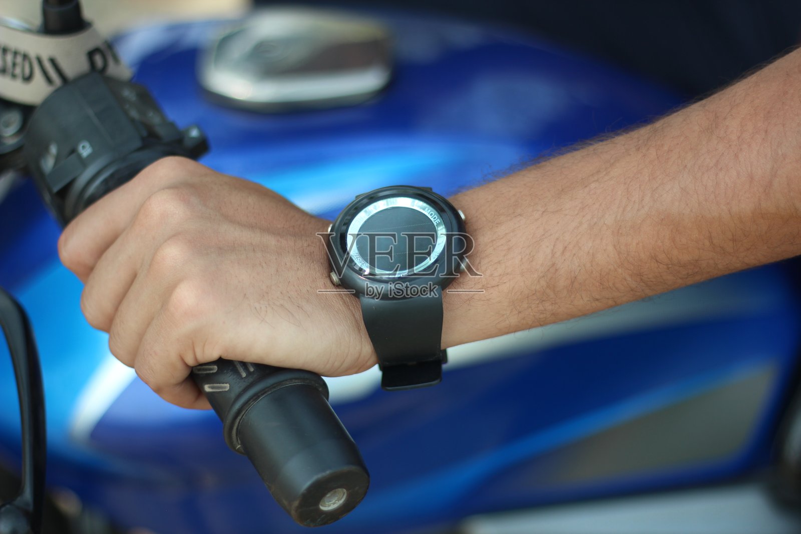 这是一个男人坐在摩托车上，手里拿着一辆摩托车，他身后的背景是模糊的照片摄影图片