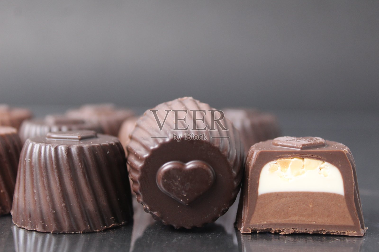 巧克力盒糖果与填充巧克力香草慕斯巧克力酱与花生坚果在黑色背景与文字的空间。糖果照片摄影图片