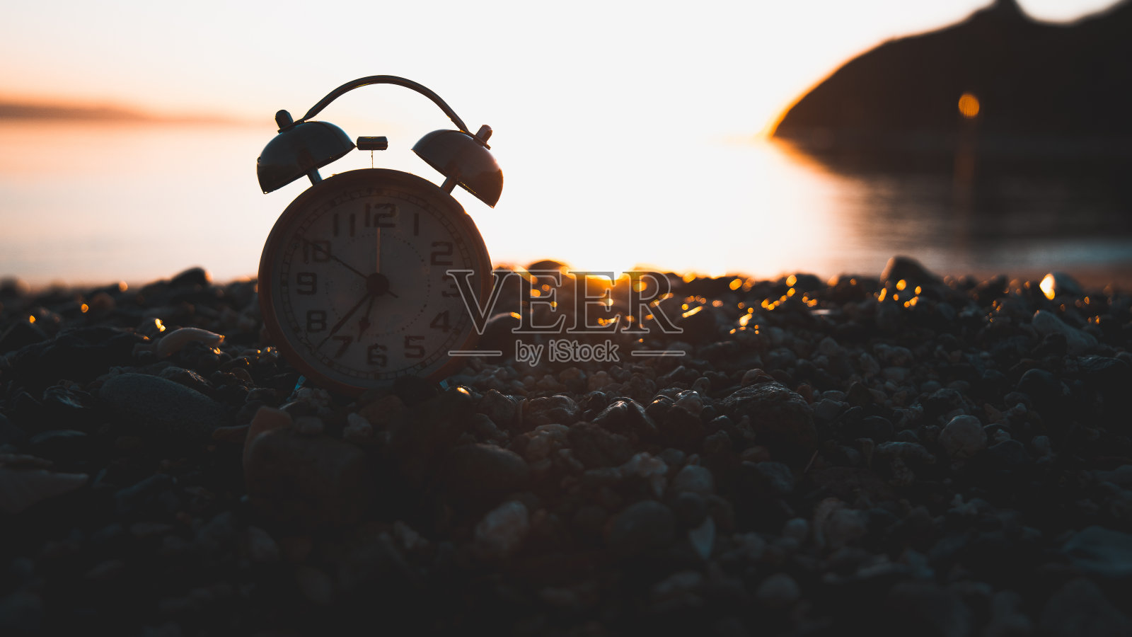 波托海滩上的复古时钟剪影，卡利亚里，日出，岩石和阳光照片摄影图片