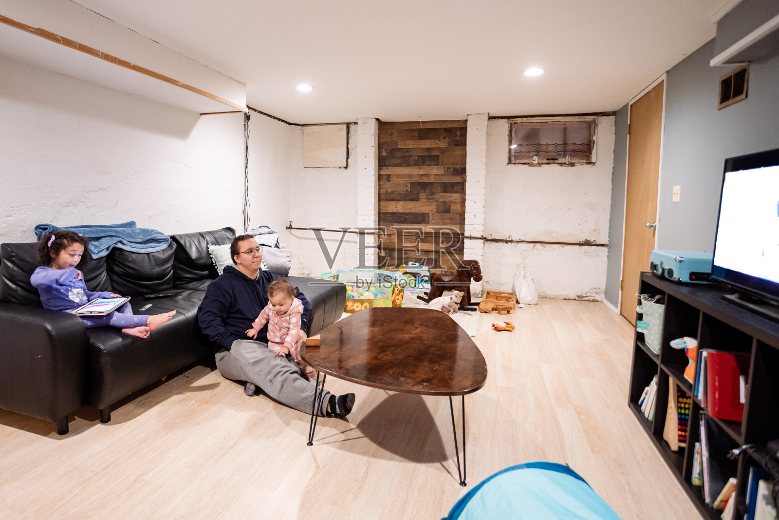 爸爸和两个女儿在家庭娱乐室看电视照片摄影图片