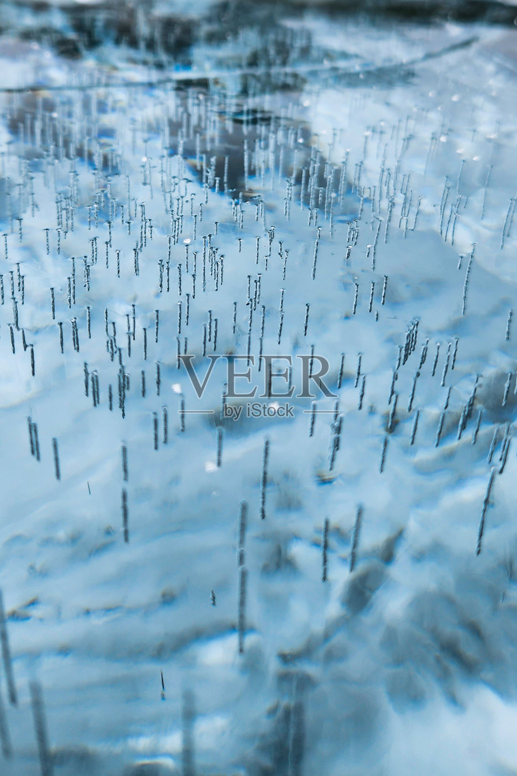 结冰的湖面上有破裂的冰。冬天结冰的湖面上有白色气泡和裂缝的冰的自然纹理。摘要明亮的背景，平面布局，布局，俯视图。照片摄影图片