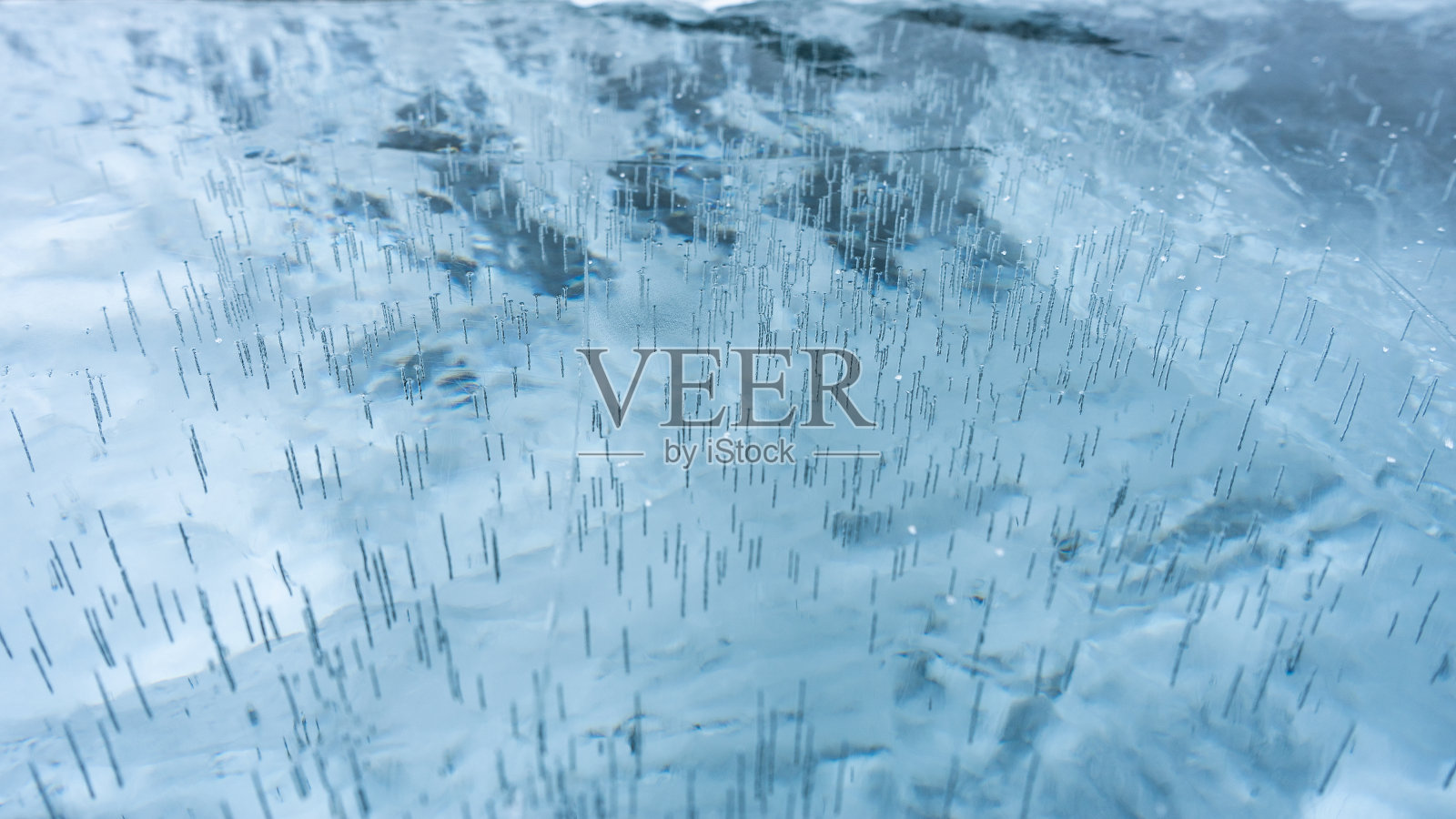 结冰的湖面上有破裂的冰。冬天结冰的湖面上有白色气泡和裂缝的冰的自然纹理。摘要明亮的背景，平面布局，布局，俯视图。照片摄影图片