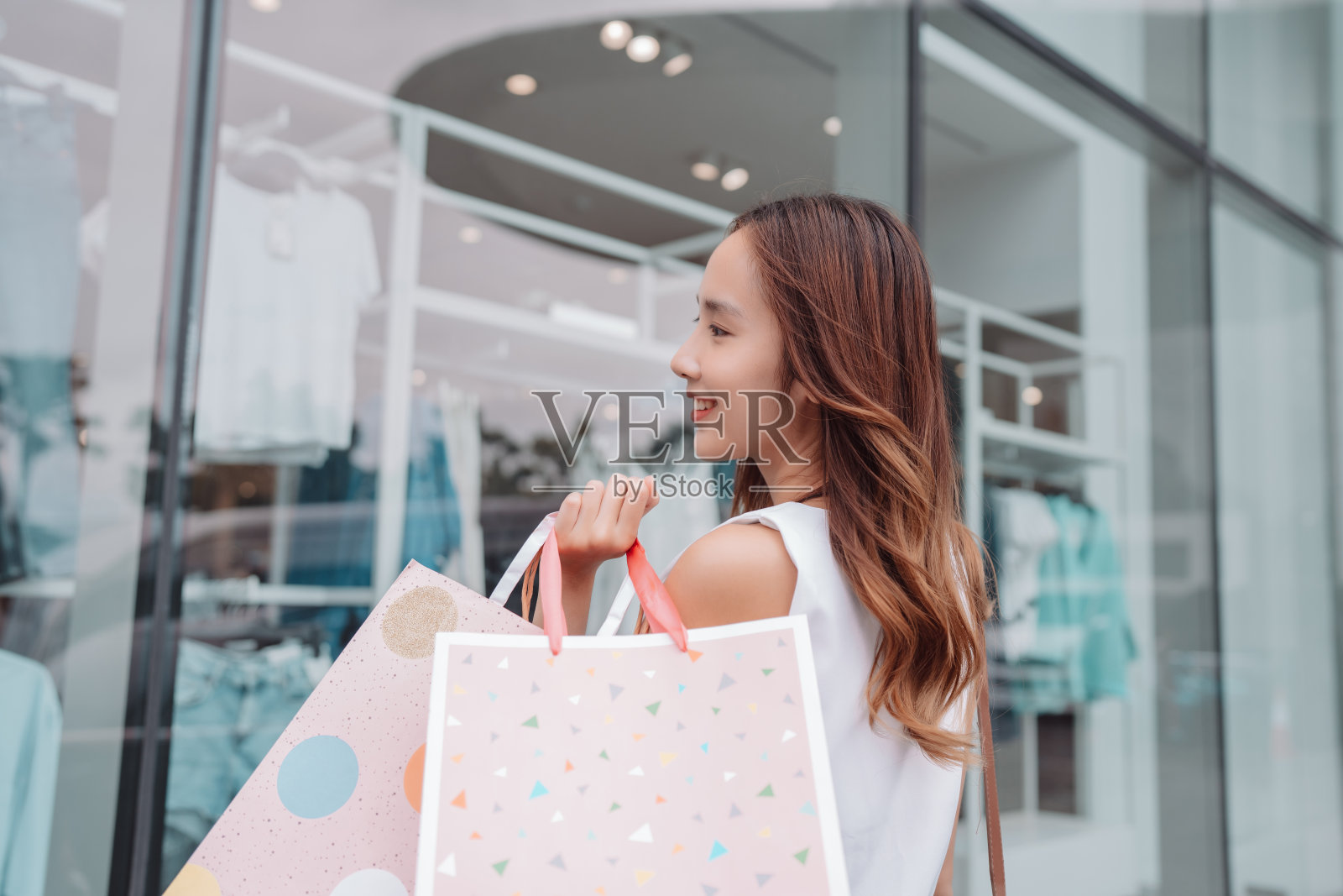 美丽的亚洲女性女子女孩拿着购物袋，散步享受微笑，在百货商场的橱窗外购物户外时尚的生活方式照片摄影图片