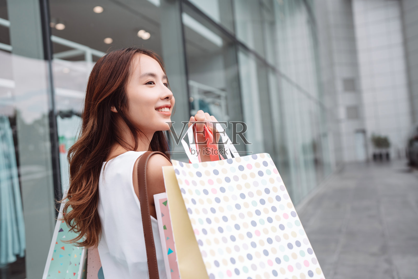 美丽的亚洲女性女子女孩拿着购物袋，散步享受微笑，在百货商场的橱窗外购物户外时尚的生活方式照片摄影图片