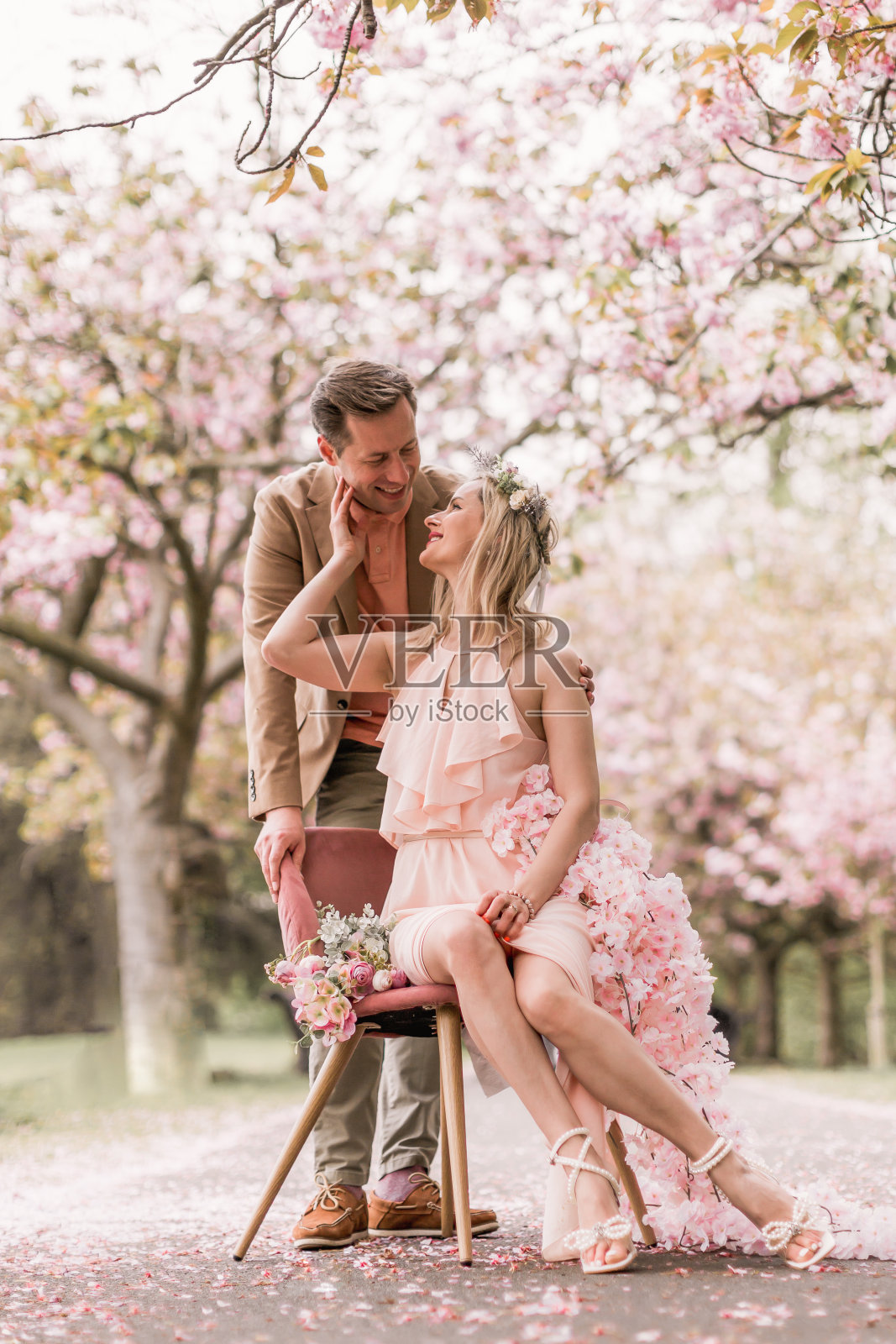 春暖花开，喜气洋洋。情侣们有浪漫的时刻。性感的夫妇女人和男人在粉红色的花在春花公园。照片摄影图片
