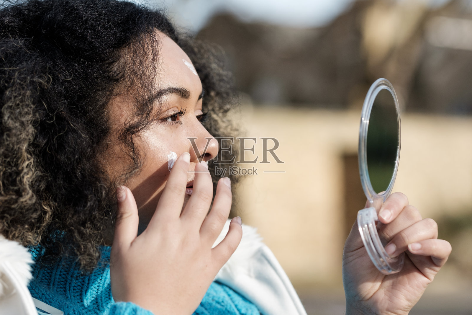 头部的曲线年轻女子适用于保湿的脸在镜子前户外。照片摄影图片
