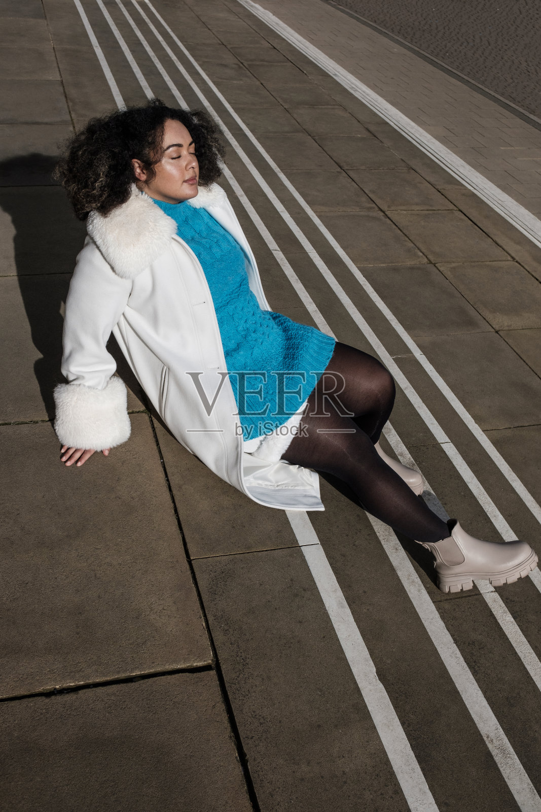 一个年轻的胖乎乎的女人坐在户外的楼梯上摆姿势。照片摄影图片