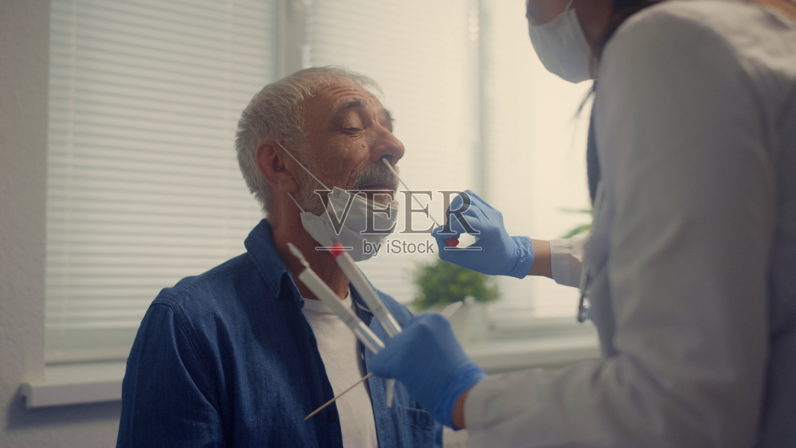 护士正在对老年男子进行鼻拭子covid检测特写。病人正在检查。照片摄影图片