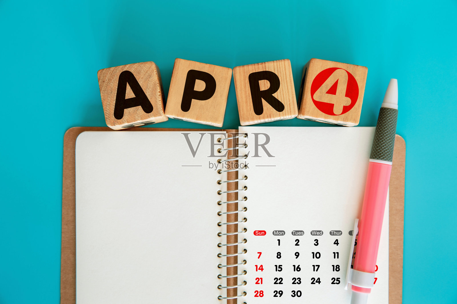 四月字在木块和空白螺旋笔记本照片摄影图片