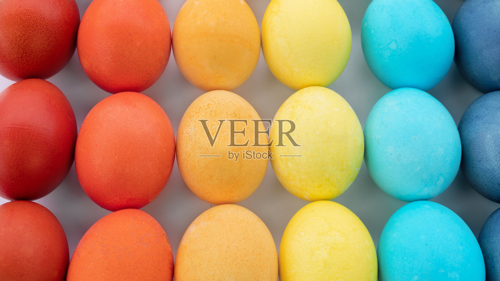 复活节彩蛋背景。鸡蛋被涂上了彩虹的相同颜色，并在白色背景上以渐变的方式摆放。快乐的复活节彩蛋在极简风格的特写照片与复制空间。照片摄影图片