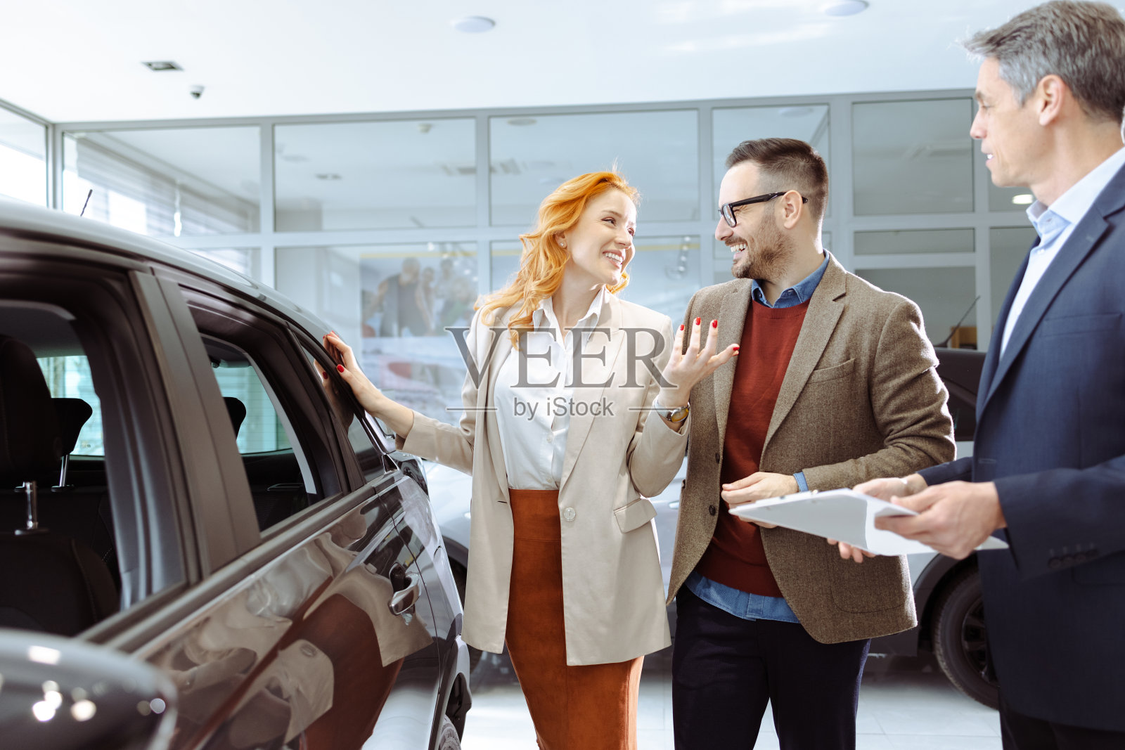 一对夫妇买了一辆新车，正在和销售人员交谈照片摄影图片