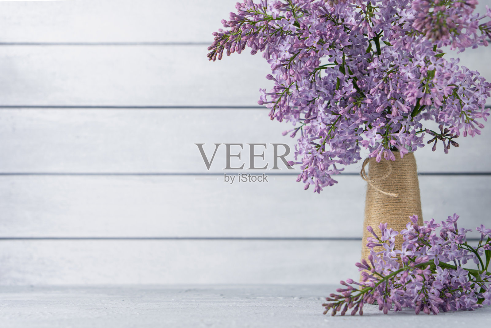 一束紫丁香花在花瓶上的灰色木制背景。背景的复制空间照片摄影图片