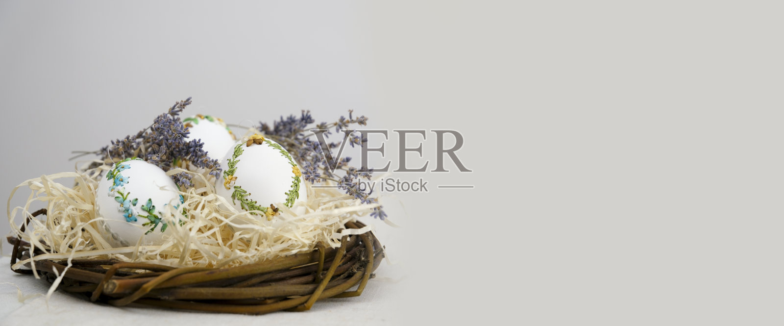 复活节假期旗帜侧面的鸡蛋在巢与薰衣草花缎带刺绣在蛋壳上白色的鸡蛋躺在稻草上对文字广告广告明信片广告牌复活节假期的空间照片摄影图片