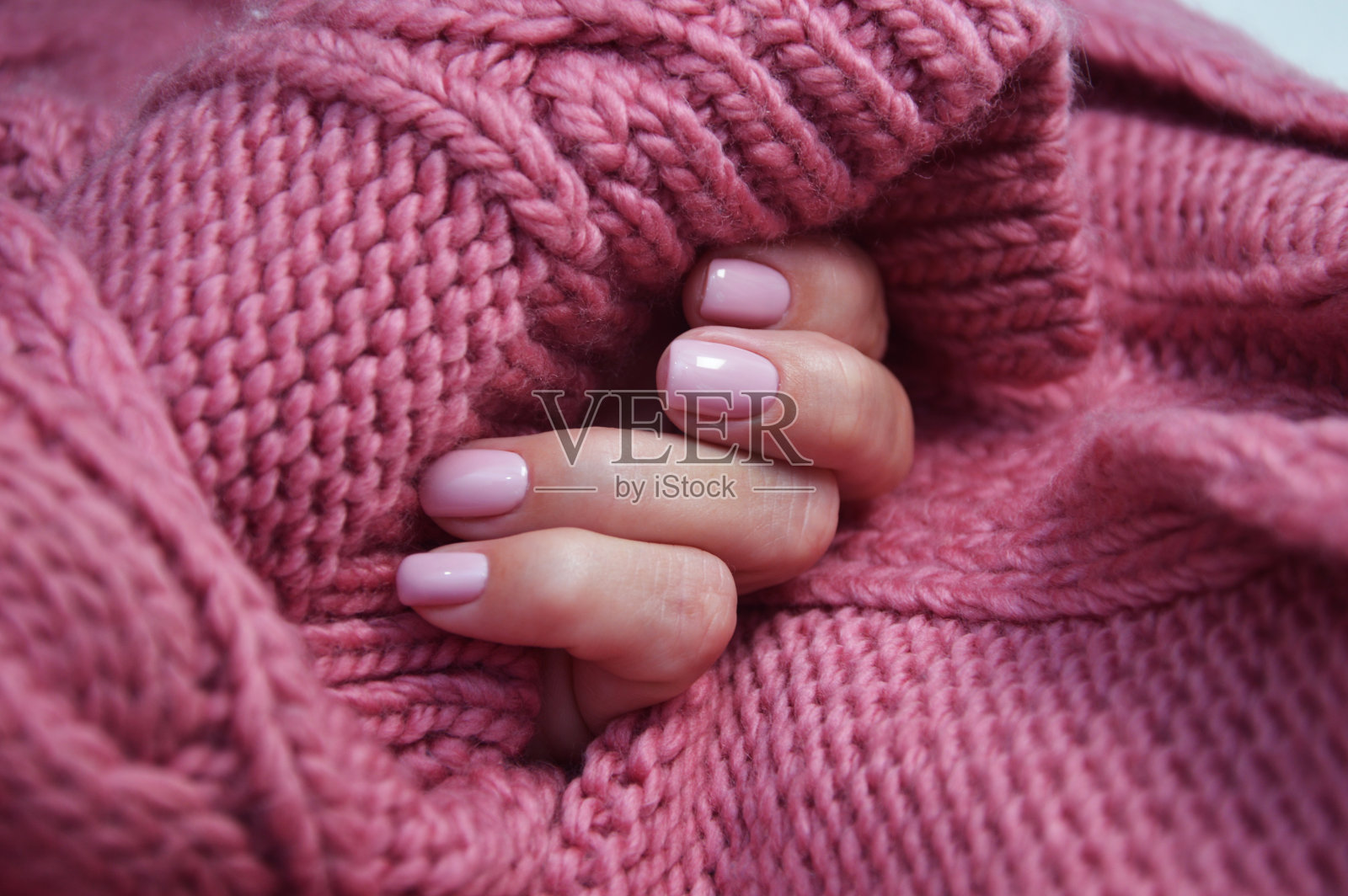 女性的手与美丽的精心修饰的指甲，自然的粉红色美甲特写背景上的粉红色针织毛衣。虫胶。照片摄影图片