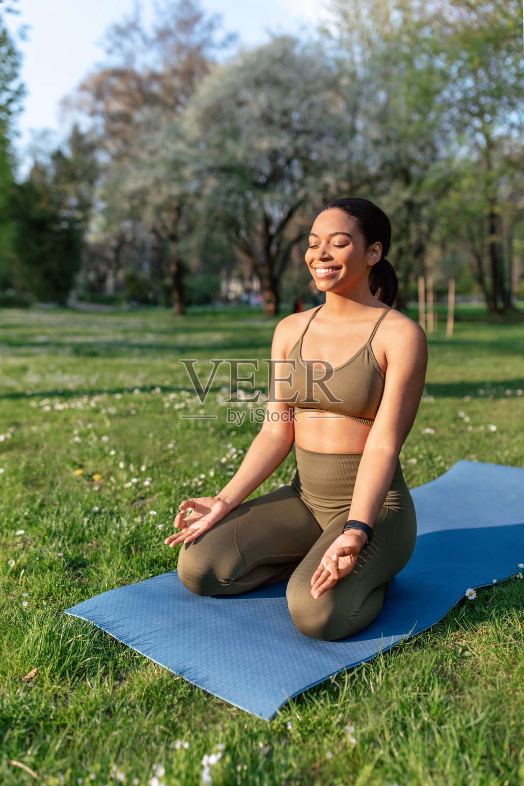 和平的千禧黑人女士坐在运动垫上，闭着眼睛在城市公园冥想，复制空间照片摄影图片