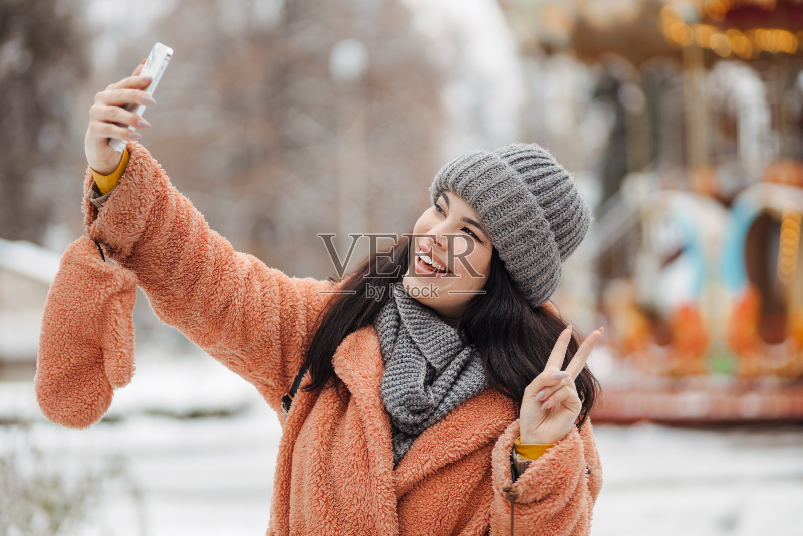 快乐的长发女人与惊人的微笑采取视频电话在冬季公园照片摄影图片