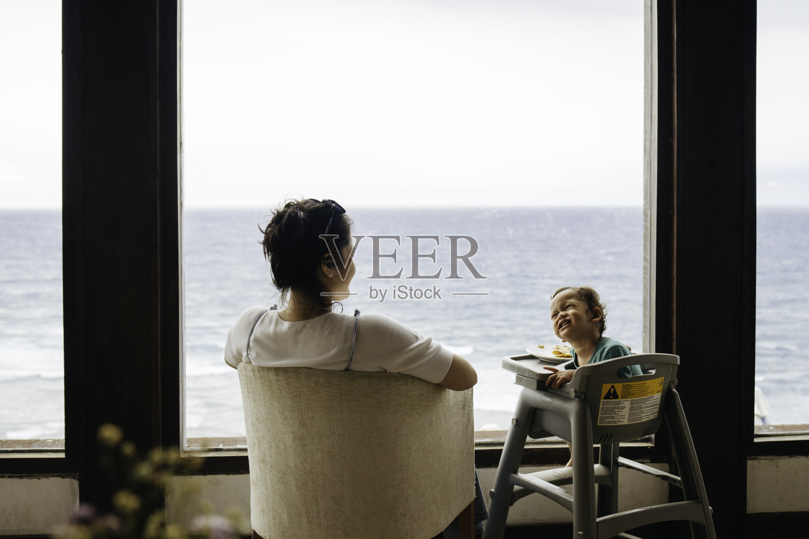 亚洲妇女和她的儿子坐在椅子上吃披萨照片摄影图片