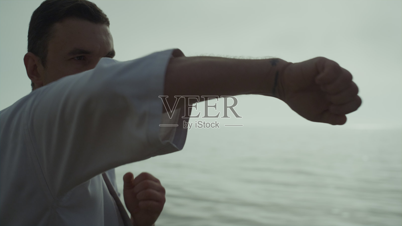 男子磨练战斗技能训练拳站在海滩上的日出接近。照片摄影图片