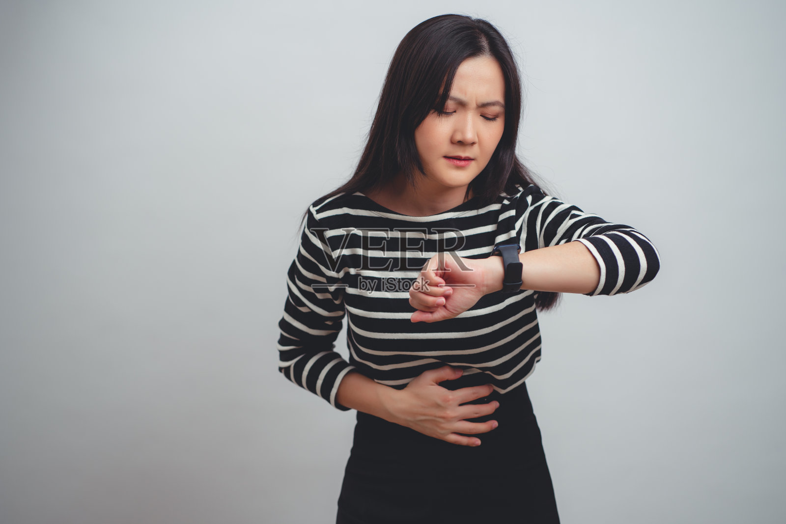 患有胃痛的亚洲妇女孤立地站在白色背景上。照片摄影图片