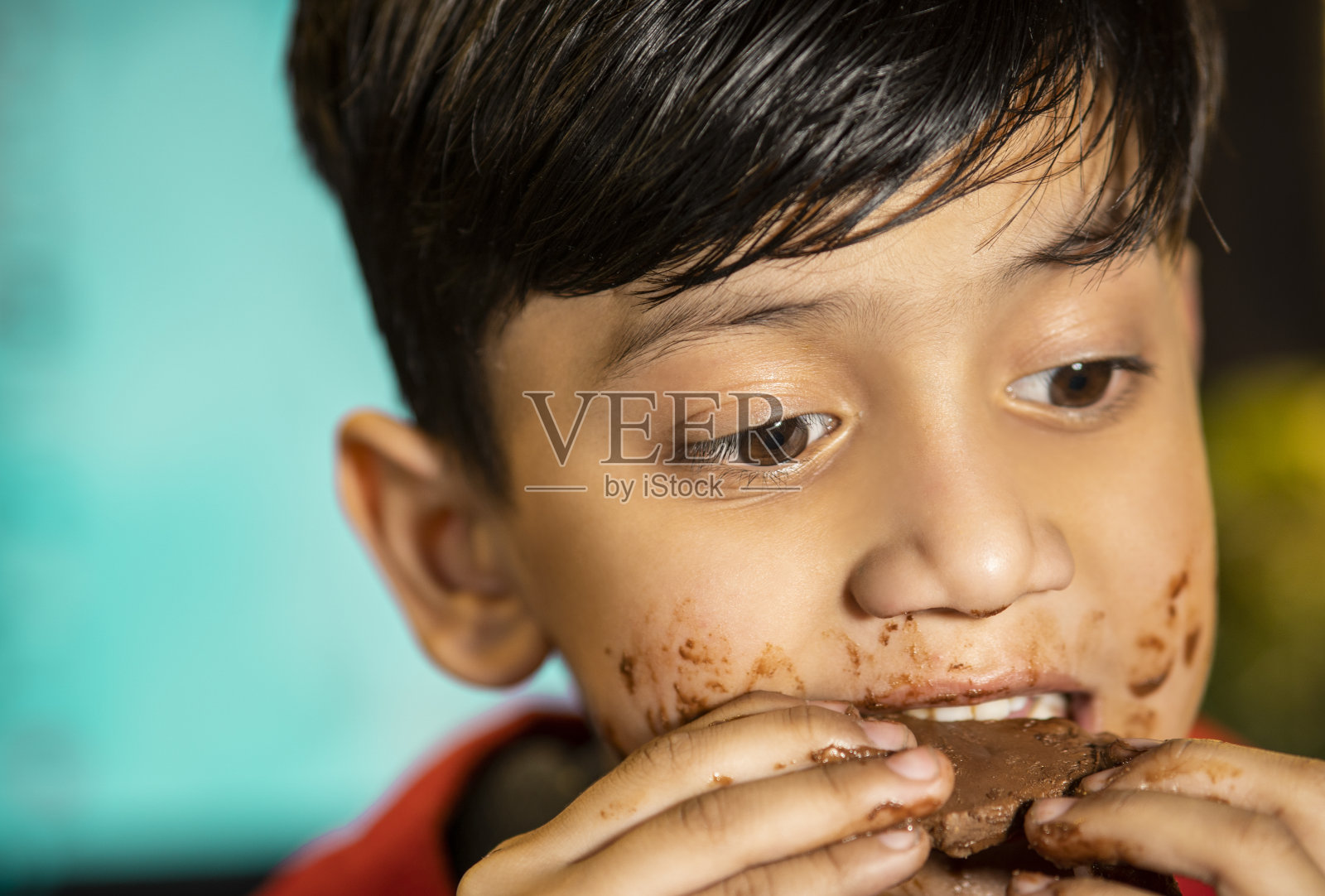 快乐的男孩吃着巧克力，尖叫了一脸。照片摄影图片