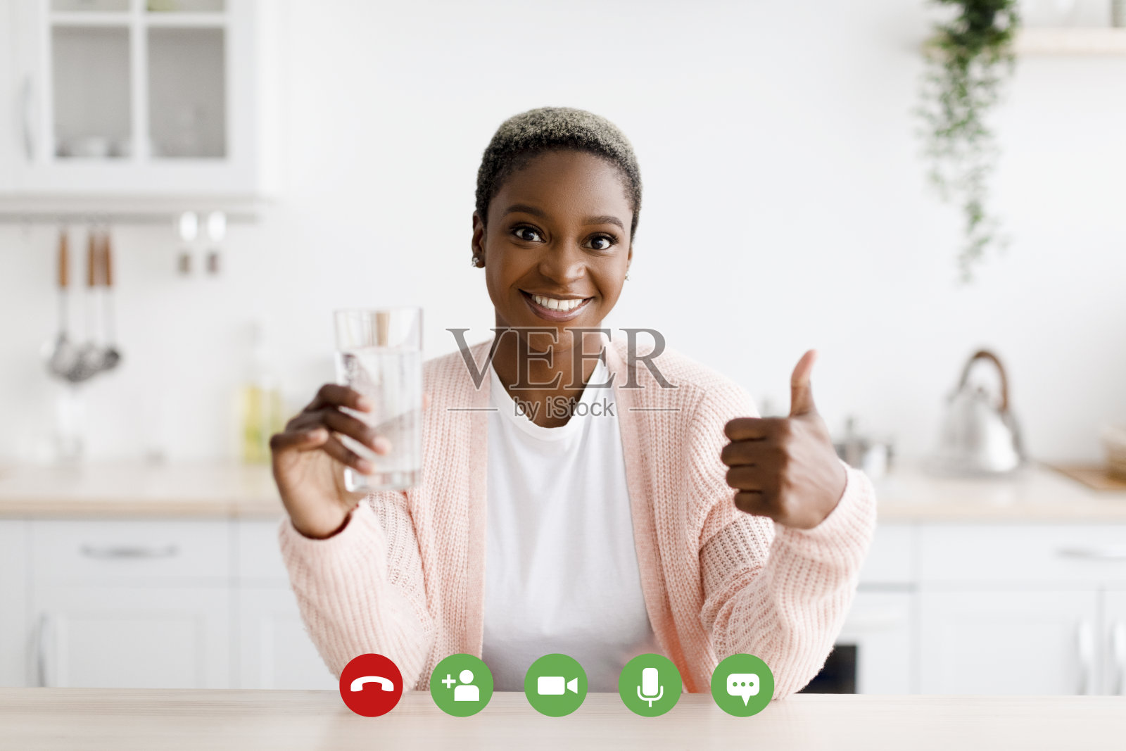 快乐的千禧一代黑人女性拿着一杯干净的水，在极简主义的厨房内部竖起大拇指照片摄影图片