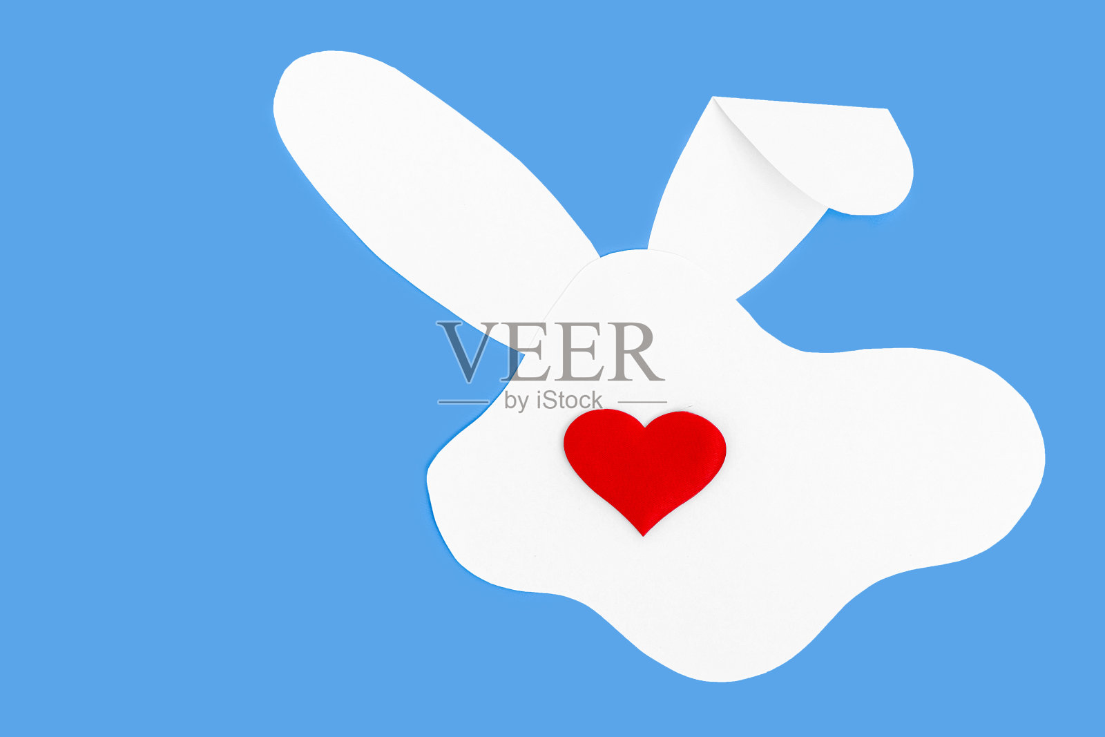 有创意的布局，在蓝色背景上用一只白纸兔子的剪影和一个红心代替了鼻子照片摄影图片