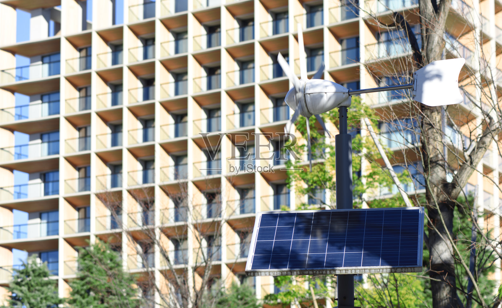 太阳能和风力发电机对着办公楼照片摄影图片